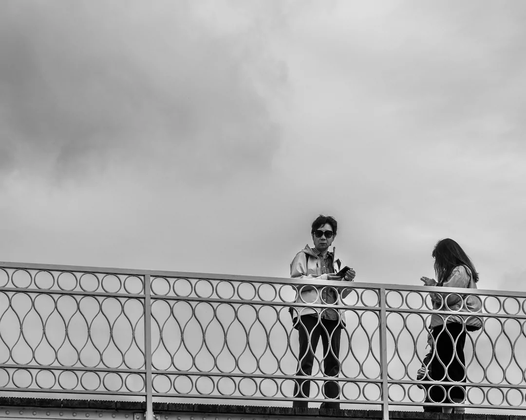 Twee mensen staan op de brug waarschijnlijk te fotograferen met hun mobiel